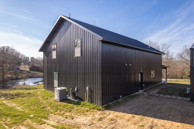 view of home's exterior featuring a water view, central air condition unit, and metal roof