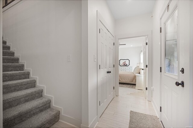 hallway featuring light wood-type flooring, stairway, and baseboards