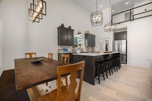 dining area featuring recessed lighting, a towering ceiling, and light wood finished floors