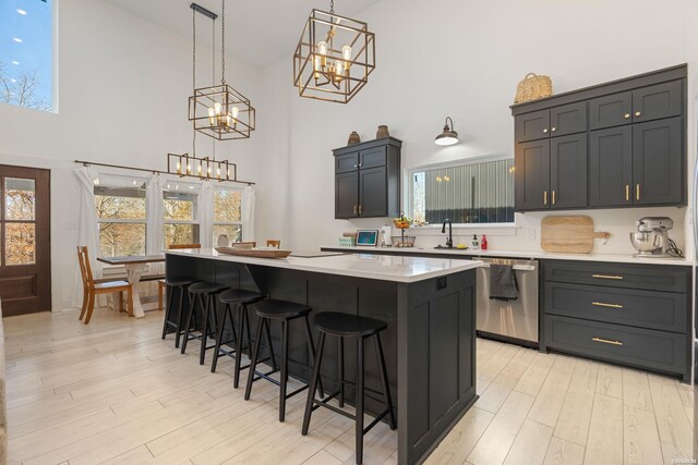 kitchen featuring a breakfast bar, light countertops, a center island, dishwasher, and pendant lighting