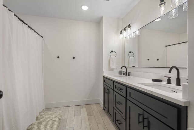 bathroom featuring double vanity, a sink, baseboards, and wood finished floors