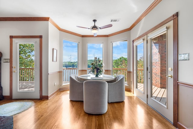 dining room featuring ornamental molding, plenty of natural light, visible vents, and light wood-style floors