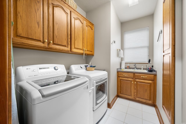 clothes washing area featuring cabinet space, baseboards, washing machine and clothes dryer, a sink, and light tile patterned flooring