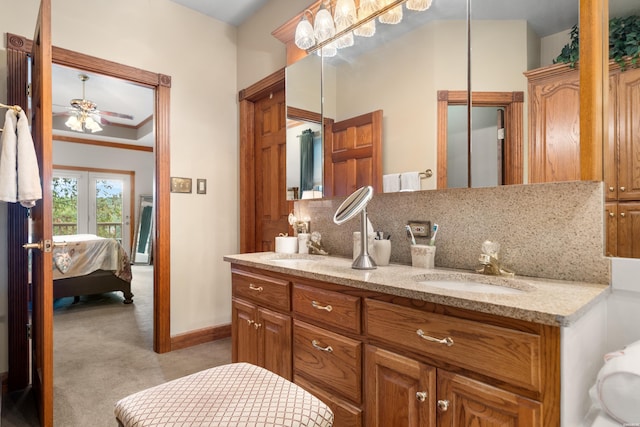 full bathroom featuring double vanity, tasteful backsplash, connected bathroom, a tray ceiling, and a sink