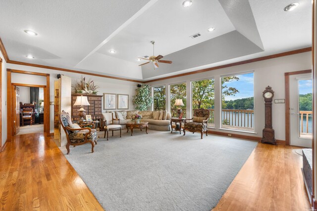 living area featuring a tray ceiling, light wood-type flooring, and visible vents