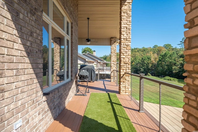 wooden deck with a ceiling fan, a yard, and a grill