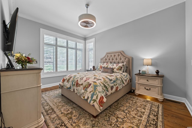 bedroom featuring dark wood-type flooring, crown molding, and baseboards