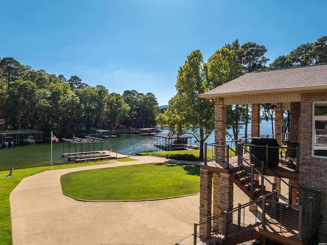 surrounding community with a dock, a water view, and a lawn