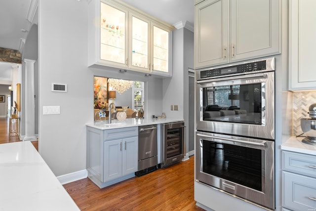 kitchen with wine cooler, stainless steel appliances, light countertops, glass insert cabinets, and ornate columns