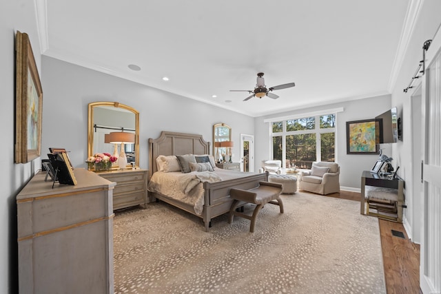 bedroom with recessed lighting, light wood-style flooring, a barn door, ornamental molding, and baseboards