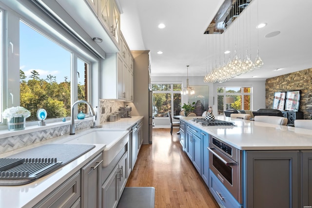 kitchen featuring hanging light fixtures, appliances with stainless steel finishes, light countertops, and a healthy amount of sunlight