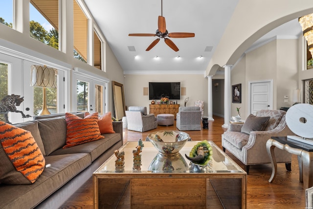 living area featuring arched walkways, french doors, dark wood-type flooring, high vaulted ceiling, and ornate columns