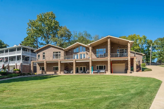 rear view of property with a garage, brick siding, a lawn, and driveway