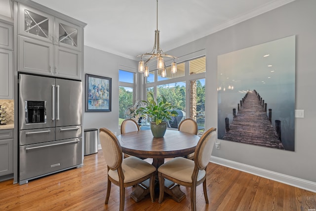 dining space featuring a notable chandelier, baseboards, stairs, ornamental molding, and light wood finished floors