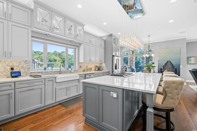 kitchen with gray cabinets, a kitchen island, light countertops, and a sink