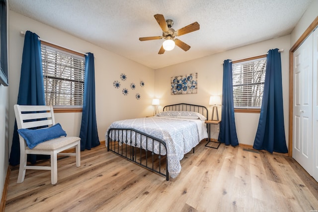 bedroom with a textured ceiling, a closet, wood finished floors, and multiple windows