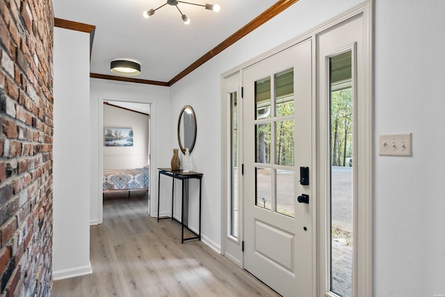 entryway with light wood-type flooring, brick wall, crown molding, and baseboards