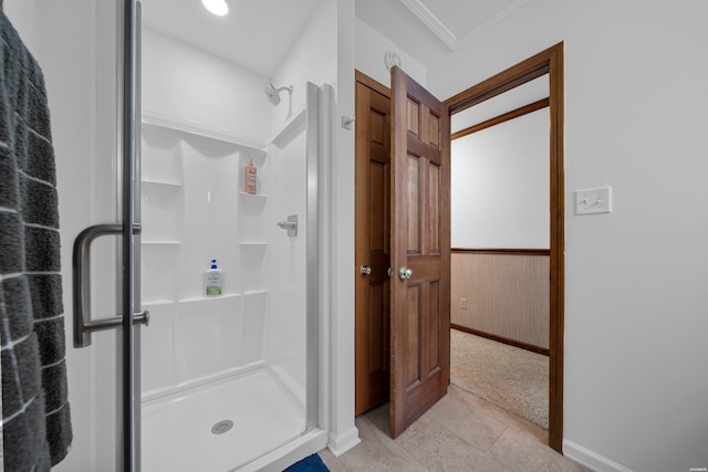 full bath with wood walls, wainscoting, crown molding, and a shower stall