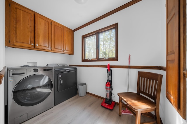 laundry area with separate washer and dryer, baseboards, ornamental molding, light wood-type flooring, and cabinet space