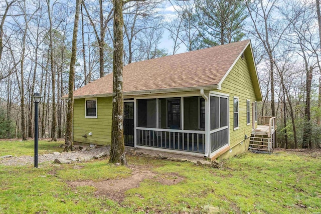 exterior space featuring a sunroom, roof with shingles, and a lawn