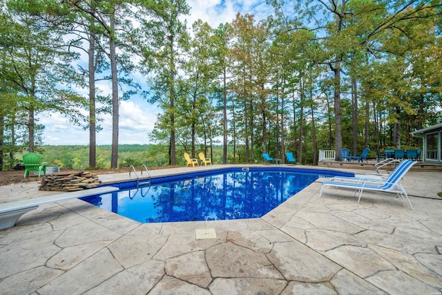 pool with a diving board and a patio