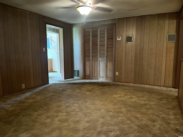 811 N 1st St, Glenwood, AR 71943 - empty room featuring ceiling fan, wooden walls, and carpet flooring