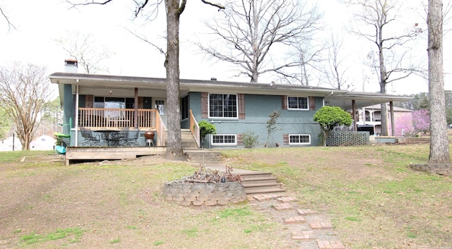 back of house featuring covered porch, brick siding, a lawn, and a chimney