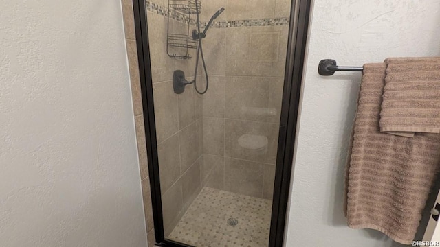 full bathroom featuring a textured wall and a shower stall