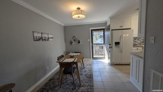 dining room with light tile patterned floors, visible vents, ornamental molding, and baseboards