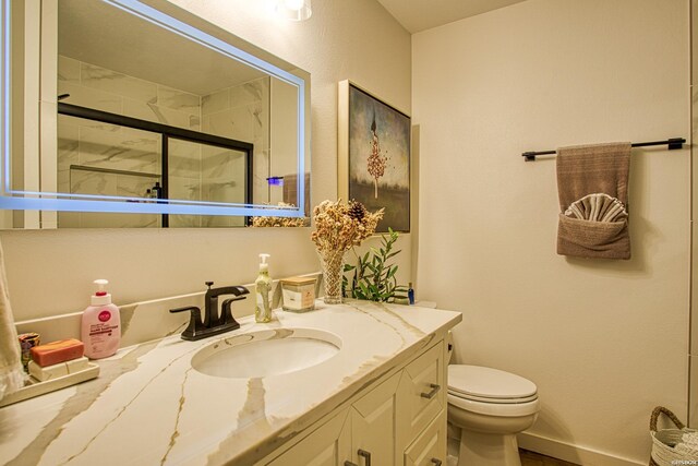 bathroom with toilet, a shower stall, vanity, and baseboards