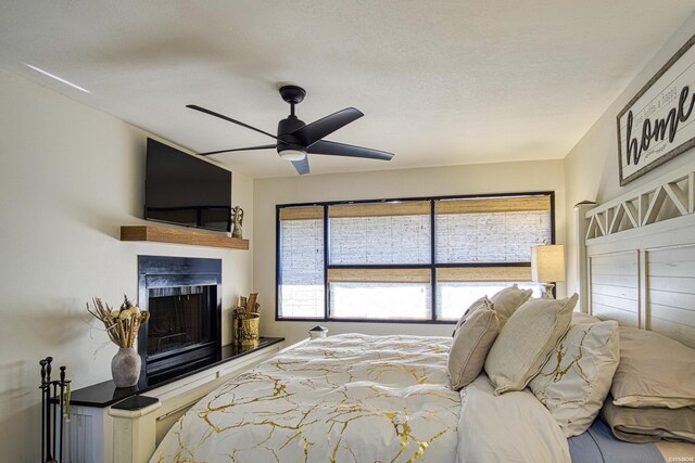 bedroom with ceiling fan and a fireplace with raised hearth