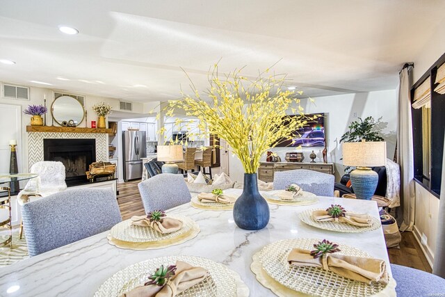 dining space featuring recessed lighting, visible vents, wood finished floors, and a tile fireplace