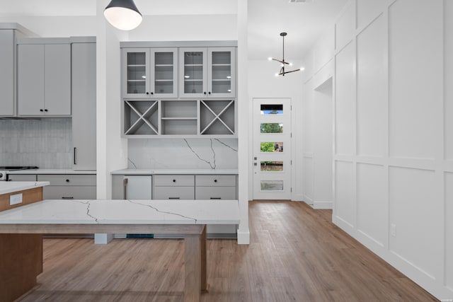 168 Krause Ln Unit B, Hot Springs, AR 71913 - kitchen with backsplash, light wood-type flooring, light stone countertops, pendant lighting, and glass insert cabinets
