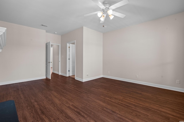 spare room with dark wood-type flooring, visible vents, baseboards, and a ceiling fan