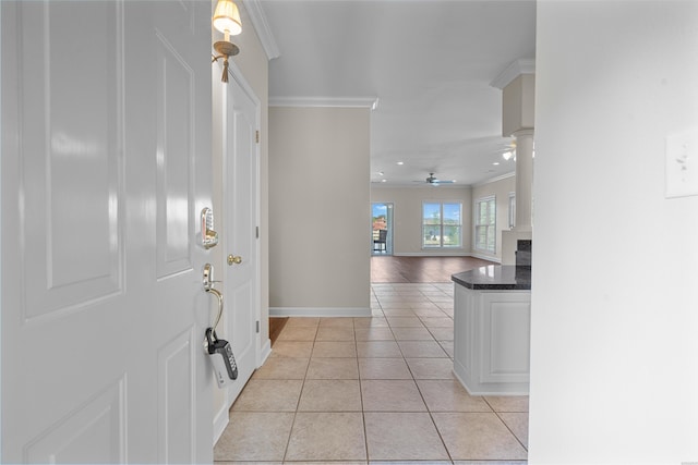 entrance foyer with a fireplace, light tile patterned floors, ornamental molding, ceiling fan, and baseboards