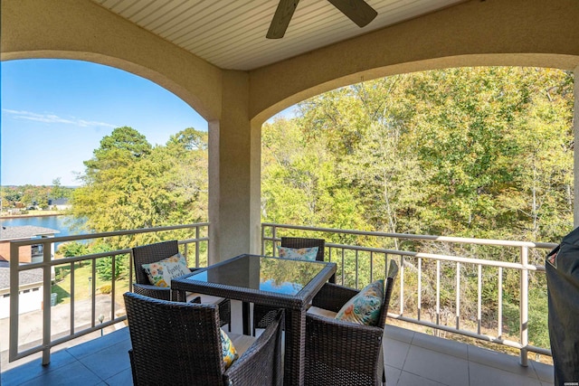 balcony featuring a water view, ceiling fan, and outdoor dining space