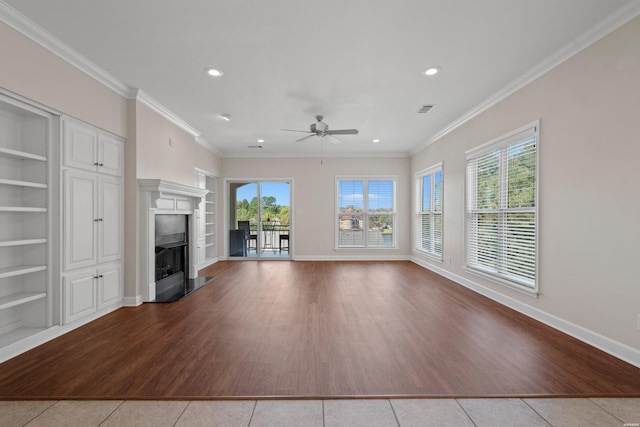 unfurnished living room with built in shelves, a fireplace, light tile patterned floors, ornamental molding, and baseboards