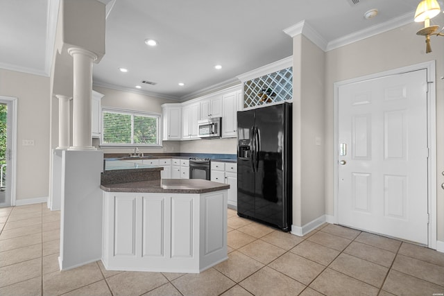 kitchen featuring stainless steel appliances, a sink, white cabinets, dark countertops, and decorative columns