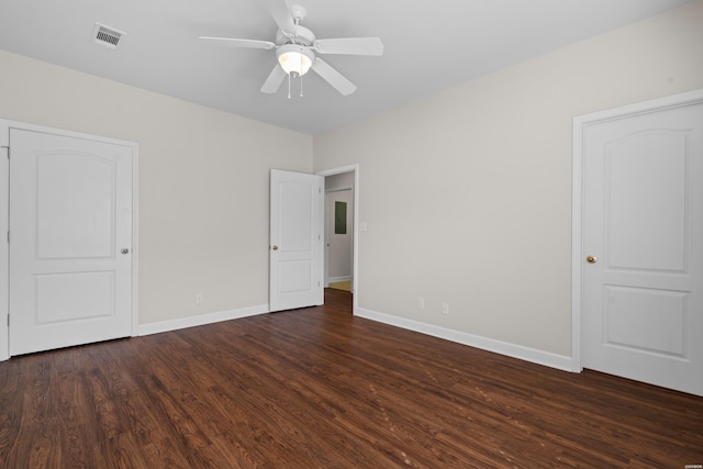 unfurnished bedroom with ceiling fan, dark wood-type flooring, visible vents, and baseboards