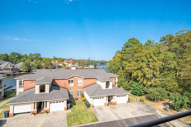 view of front of home featuring a garage, a water view, a shingled roof, and driveway