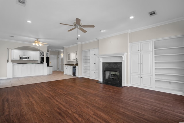 unfurnished living room featuring ornamental molding, a high end fireplace, visible vents, and a ceiling fan