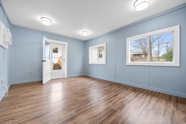 unfurnished bedroom featuring a decorative wall, baseboards, and wood finished floors