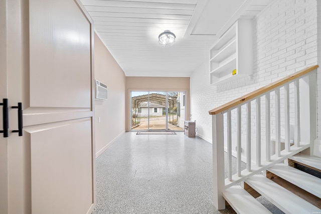 foyer entrance with brick wall, speckled floor, and baseboards