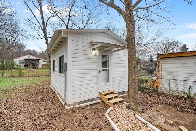 view of outbuilding featuring entry steps, an outbuilding, and fence