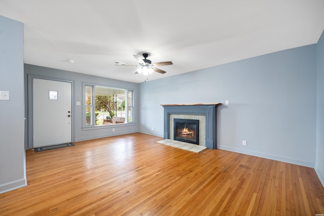 unfurnished living room with a fireplace, light wood-style flooring, and baseboards