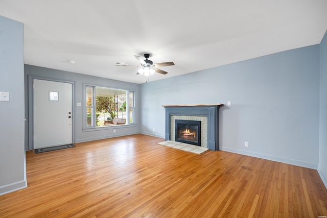 unfurnished living room featuring light wood-style flooring, baseboards, a fireplace, and ceiling fan