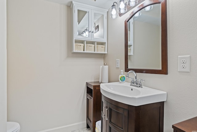 bathroom with baseboards, toilet, and vanity