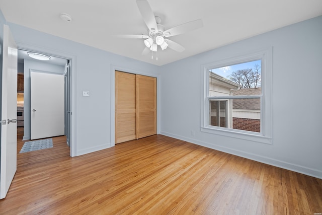 unfurnished bedroom with light wood finished floors, a ceiling fan, baseboards, and a closet