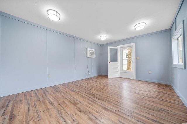 unfurnished room with a wall unit AC and wood finished floors