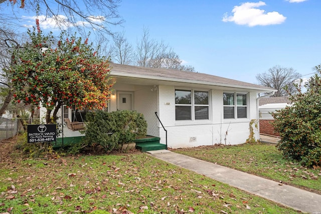 view of front facade featuring a porch, brick siding, a front yard, and crawl space